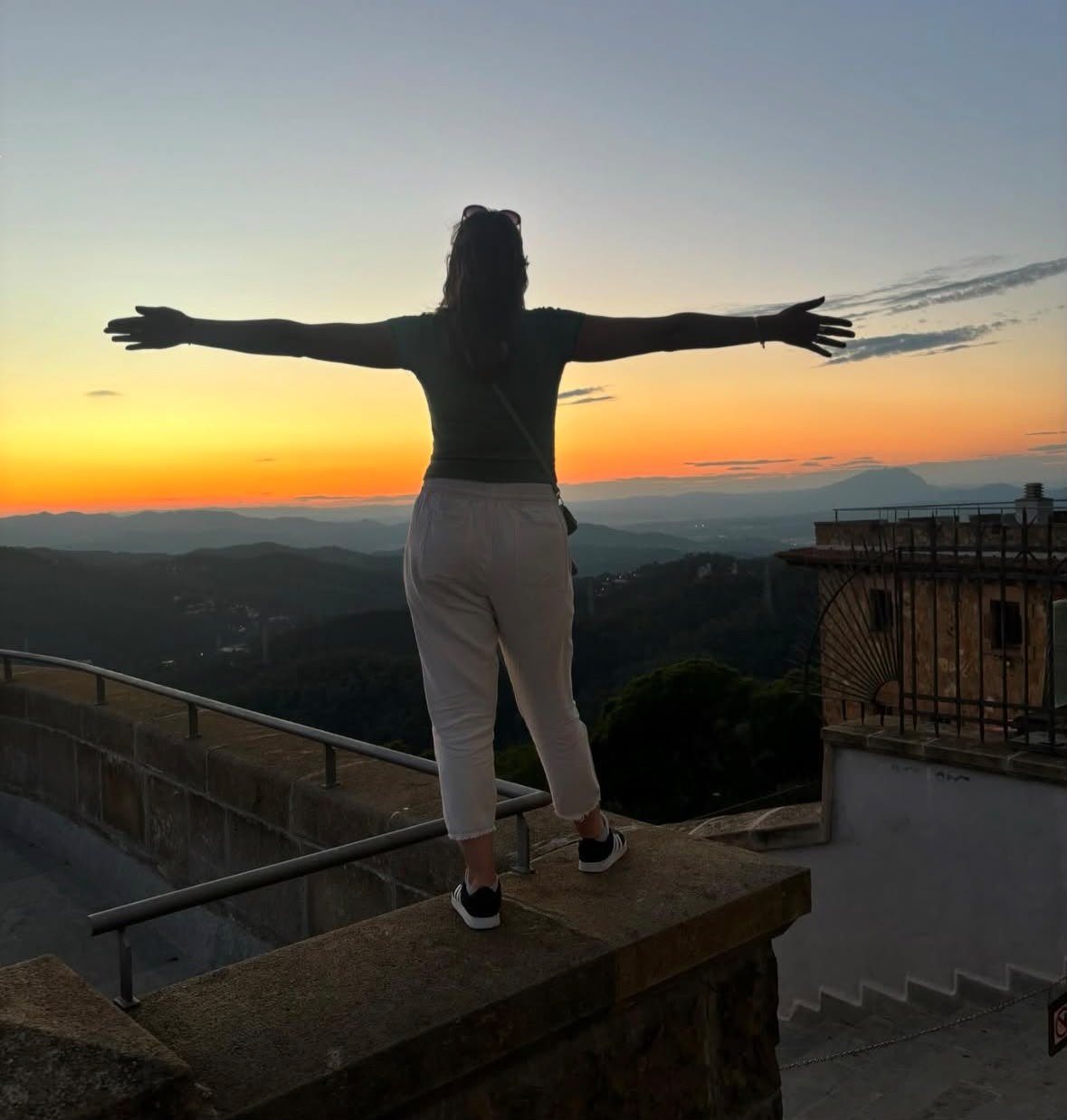 Paola Guarino con los brazos abiertos frente a las montañas al atardecer
