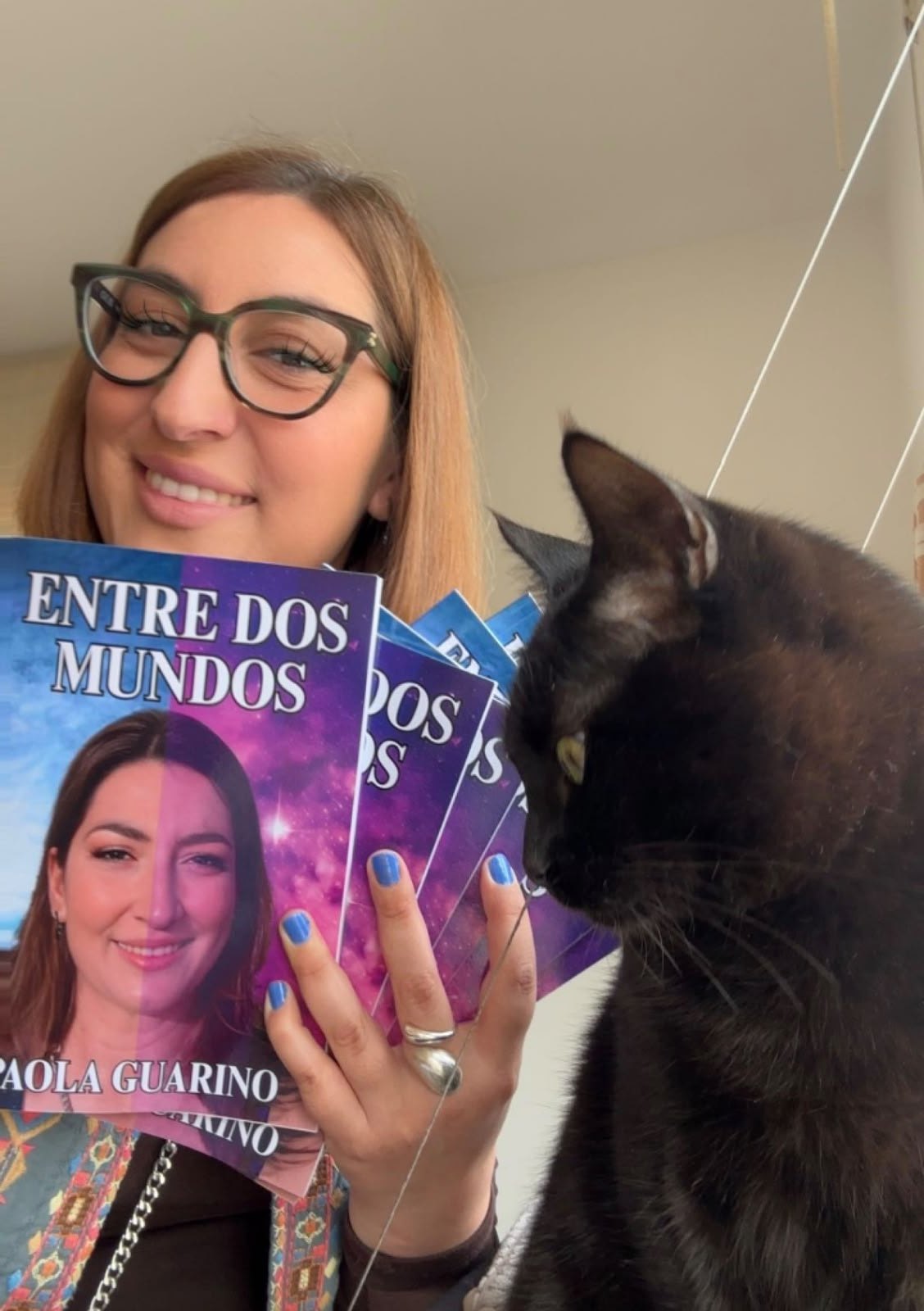 Paola Guarino con varios ejemplares de Entre Dos Mundos y su gata
